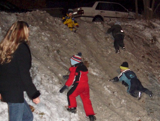 Weihnachtsbaumfeuer - Kinder rutschen im Schnee die B&ouml;schung herunter