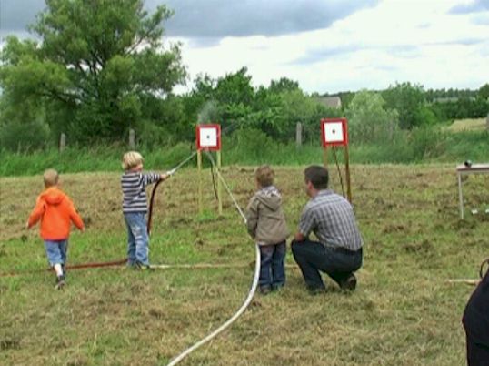 Kinder zielen mit dem Wasserstrahl auf eine Zielscheibe